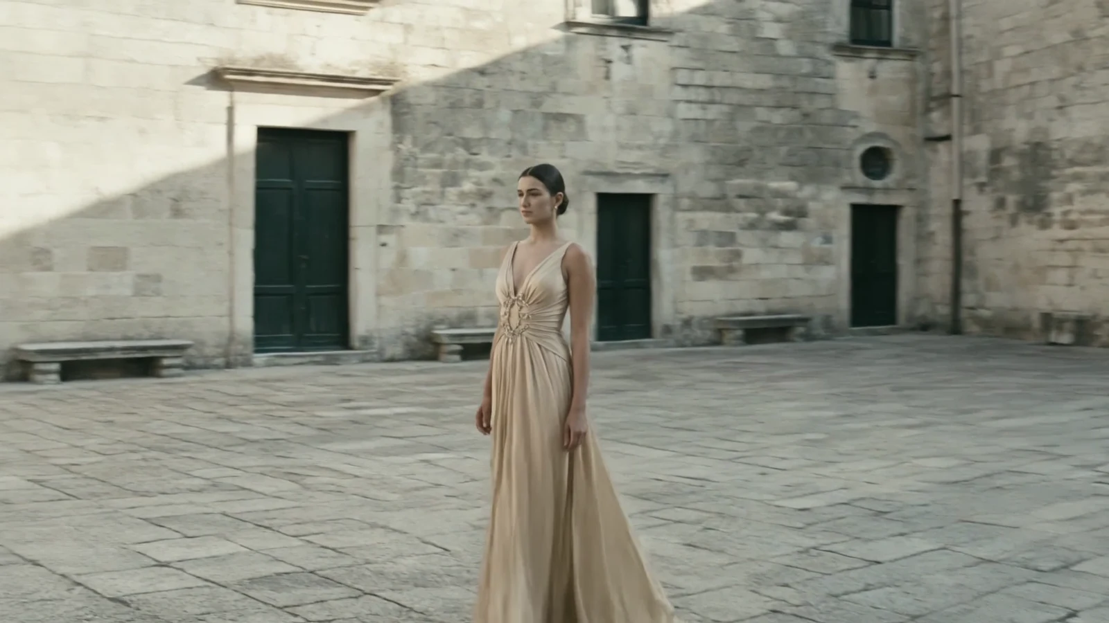 Model wearing an evening dress in a stone courtyard
